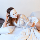 woman using LED light mask at home