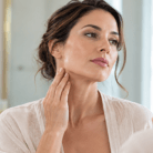 thumbnail younger woman in her 30s examining neck and jaw in mirror